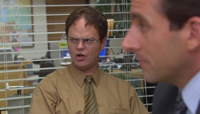 Dwight Schrute speaking with someone with an annoyed expression