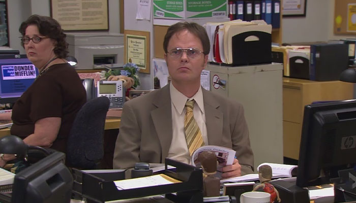 Dwight Schrute looking from over his table with an empty look