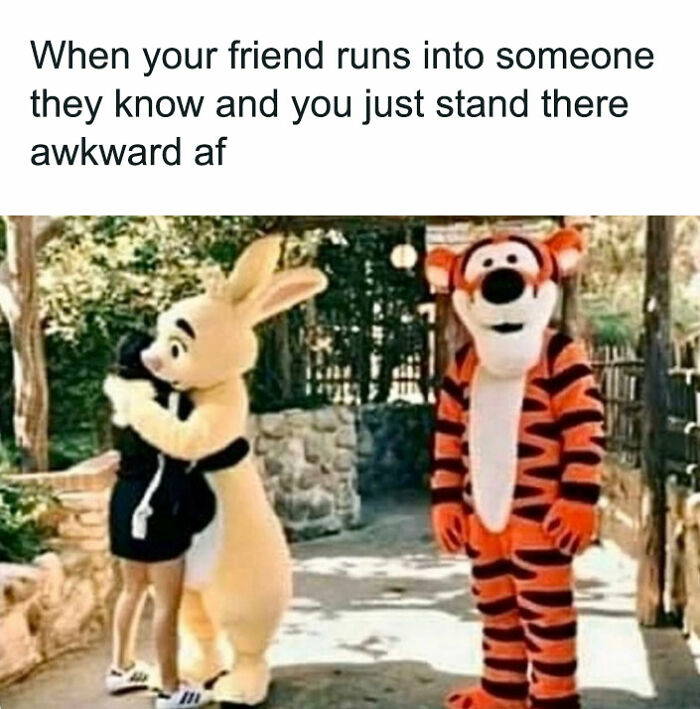 Tigger standing awkwardly beside a hugging pair, capturing a funny friendship moment.