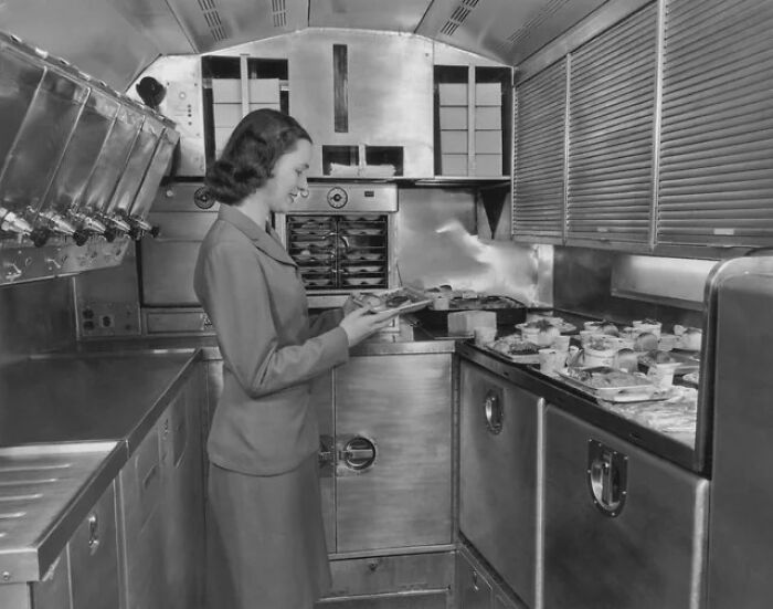 A Pan American World Airways Flight Attendant Preparing In-Flight Meals In The Galley Of An Airliner, Circa 1950