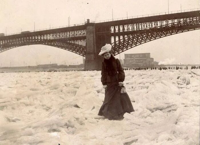 The Mississippi River Freezes Solid In February 1905. A Woman Standing On The Mississippi River Beneath The Eads Bridge At St. Louis, Missouri, With Dozens Of People Behind Her Seen Walking Across The Frozen River
