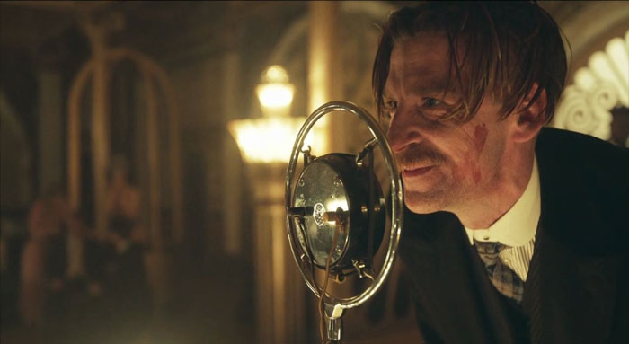 Arthur Shelby smiling behind a microphone