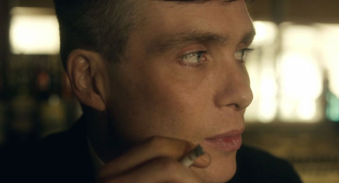 Tommy Shelby looking to his left and smoking a cigarette in a close up shot