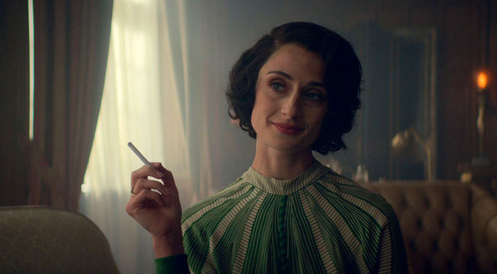 Lizzie Shelby holding a cigarette and smiling
