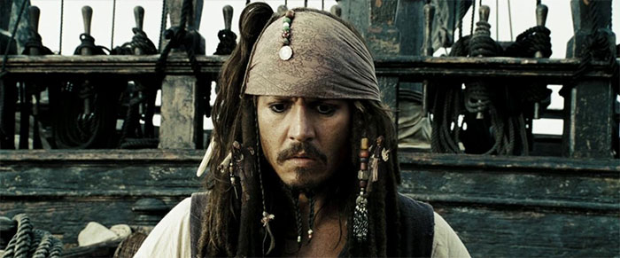 Jack Sparrow looking down while standing on ship 