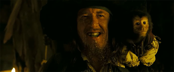 Captain Barbossa with money on his shoulder smiling 