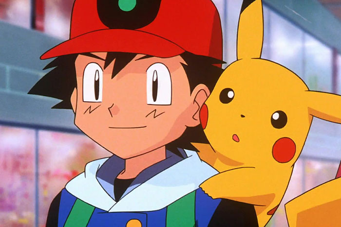 Ash Ketchum smiling and Pikachu is on his back