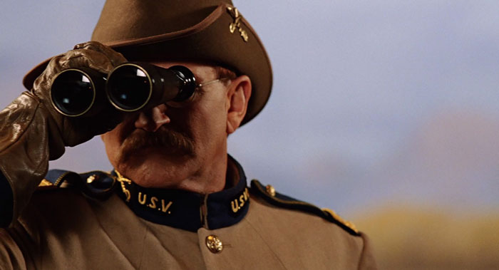 Robin williams looking through binoculars as teddy Roosevelt in night in a museum