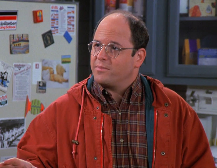 George from Seinfeld wearing a red jacket and plaid shirt, representing funniest Seinfeld quotes about everyday life.