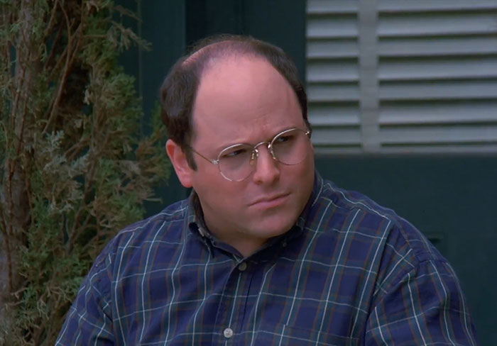 George from Seinfeld wearing glasses and a blue shirt, captured in a moment reflecting funniest Seinfeld quotes about everyday life.
