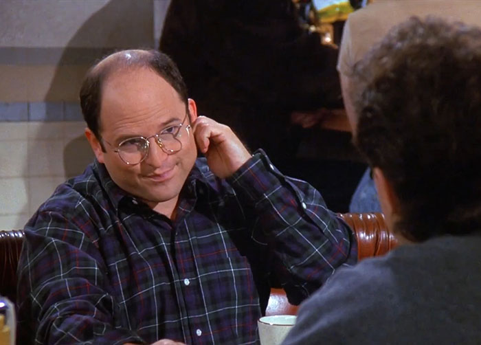 George wearing a dark purple shirt during a classic Seinfeld scene, showcasing funniest Seinfeld quotes about everyday life.