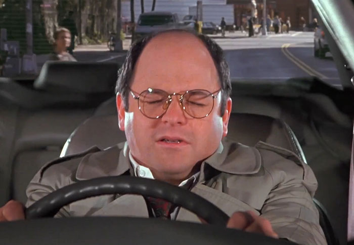George from Seinfeld wearing a gray jacket behind the wheel, capturing a moment from funniest Seinfeld quotes about everyday life.