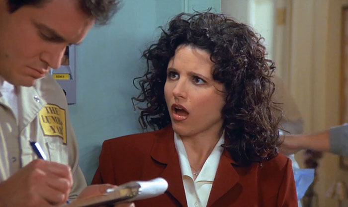 Elaine wearing white shirt and red suit reacting with surprise, illustrating funniest Seinfeld quotes about everyday life.