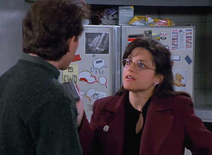 Elaine in a red jacket and black shirt interacting in a kitchen scene from Seinfeld, highlighting funniest Seinfeld quotes.