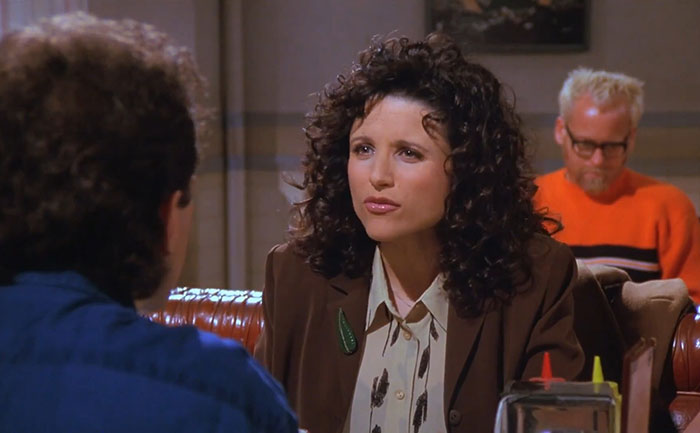 Elaine from Seinfeld wearing a brown suit and yellow shirt, captured in a scene reflecting funniest Seinfeld quotes.