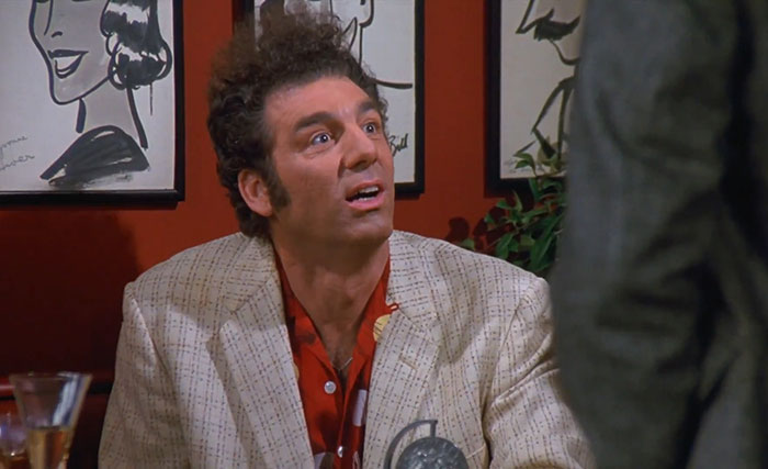 Cosmo Kramer wearing a checked suit and red shirt, captured in a scene reflecting funniest Seinfeld quotes about everyday life.