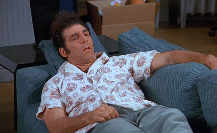 Cosmo Kramer in colorful white shirt lounging on couch, reflecting the funniest Seinfeld quotes about everyday life.