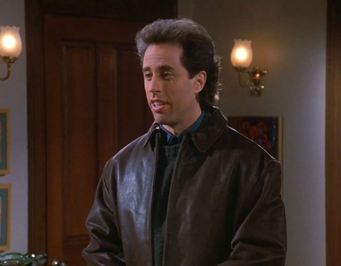 Jerry Seinfeld wearing a brown jacket delivering one of the funniest Seinfeld quotes about everyday life moments.