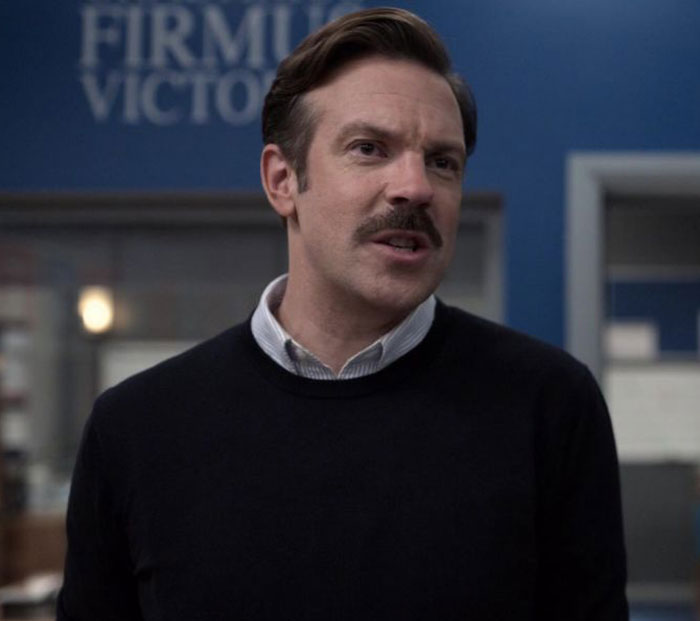 Ted Lasso wearing black sweater and white shirt