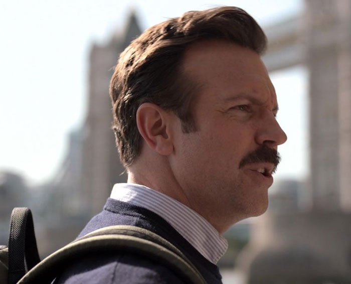Ted Lasso wearing black sweater and white shirt