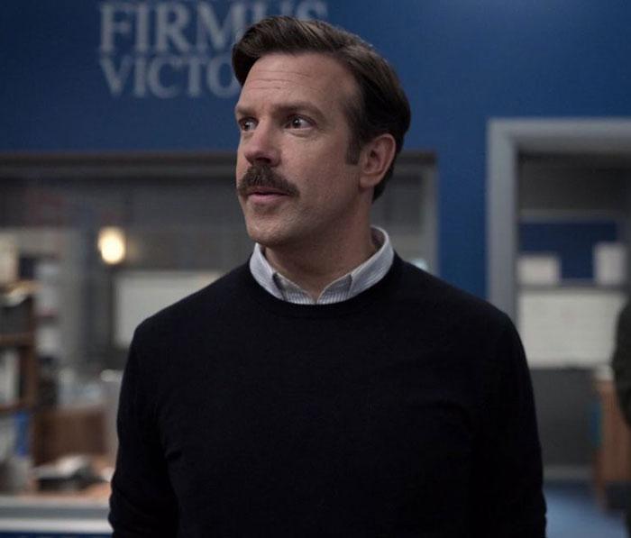 Ted Lasso wearing black sweater and white shirt