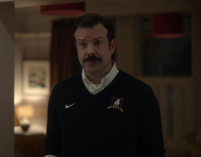 Ted Lasso wearing blue sweater and white shirt