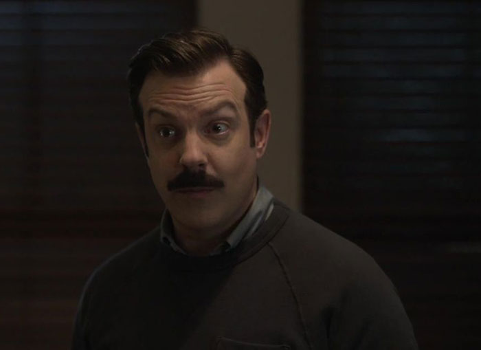 Ted Lasso wearing brown sweater and white shirt