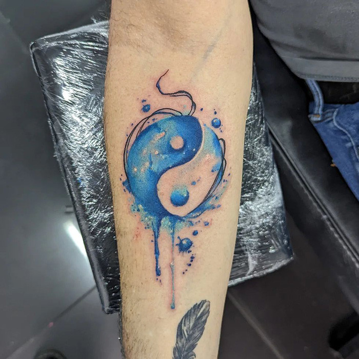 Blue yin yang symbol arm tattoo