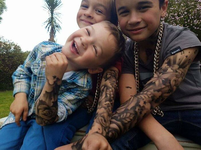 Children enjoying spray-on tattoos, smiling and playful, with detailed designs on their arms.