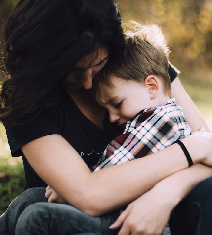Mother hugging her son outdoors, reflecting on rich grandparents' promise of inheritance and her concerns about it. Mother hugging her son outdoors, reflecting on rich grandparents' promise of inheritance and her concerns about it.