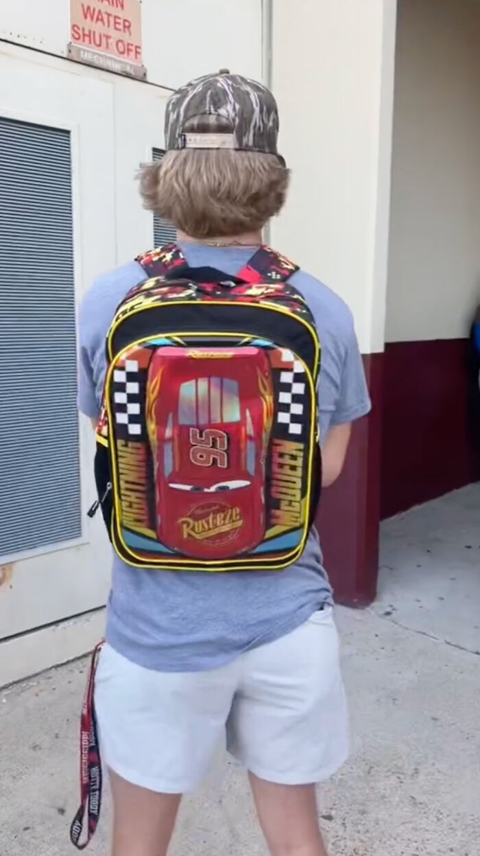 High school senior wearing a colorful Lightning McQueen kindergarten backpack outside a building. High school senior wearing a colorful Lightning McQueen kindergarten backpack outside a building.