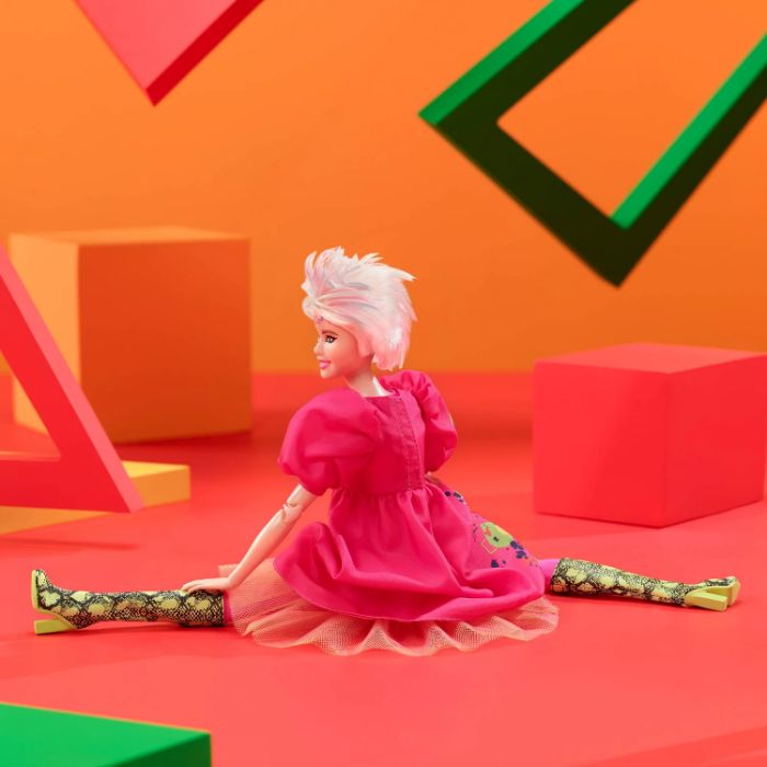 Weird Barbie doll with pink hair and dress, posed in a colorful setting with geometric shapes. Weird Barbie doll with pink hair and dress, posed in a colorful setting with geometric shapes.