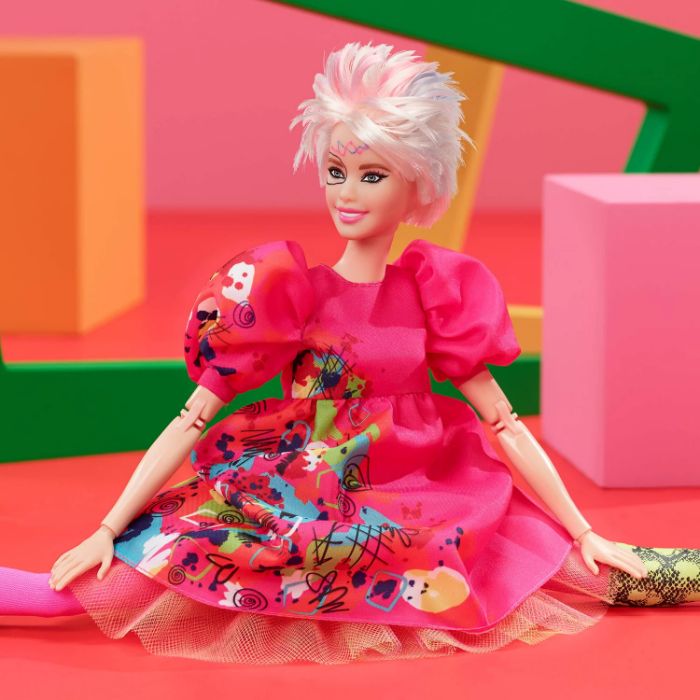 Weird Barbie doll in bright, eclectic outfit, sitting against a colorful geometric background. Weird Barbie doll in bright, eclectic outfit, sitting against a colorful geometric background.