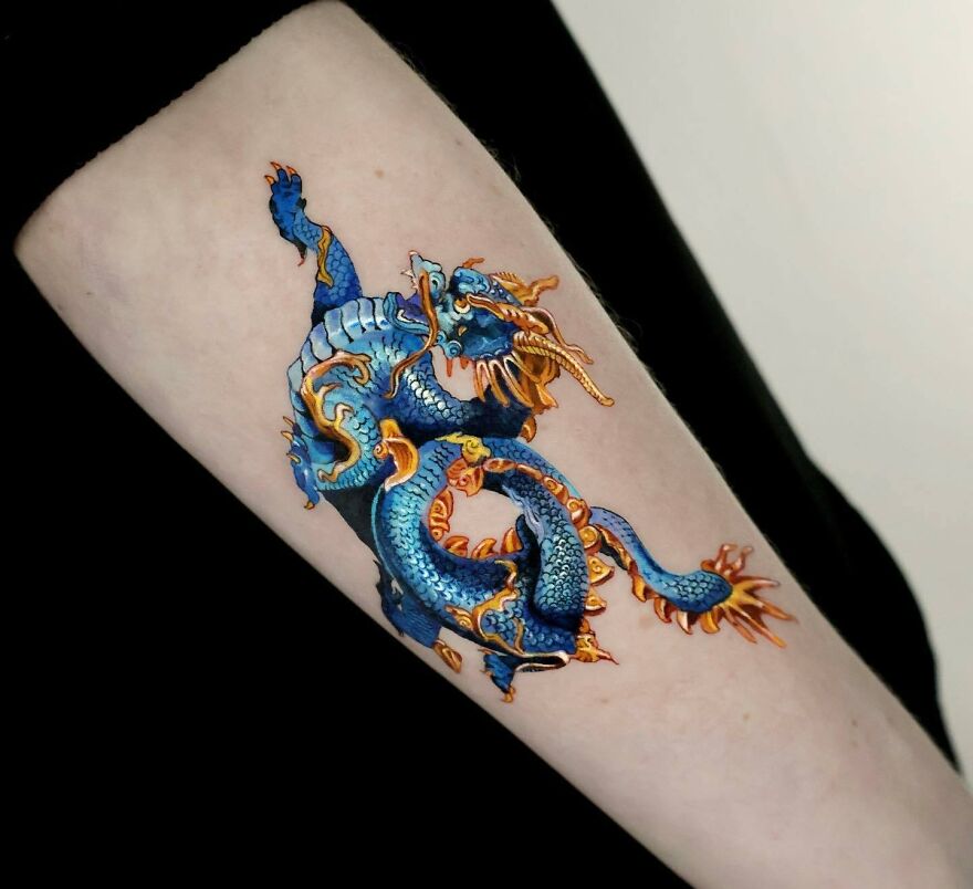 realistic tattoo of a dragon in blue and golden colored ink