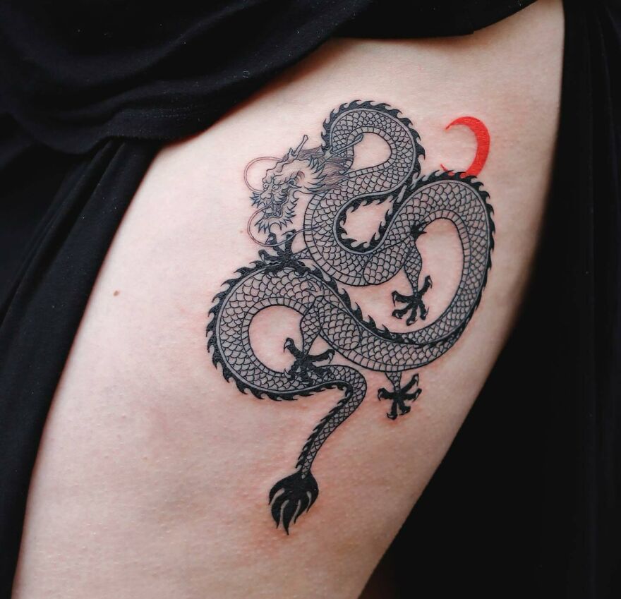 black ink dragon tattoo with a red crescent moon in the background