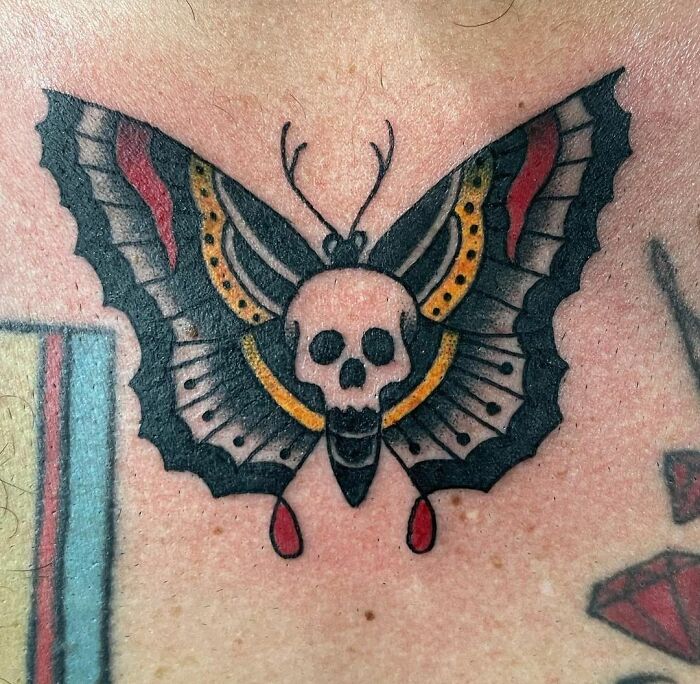 Skull and butterfly American traditional tattoo design on skin.