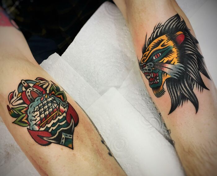 Colorful American traditional tattoo designs featuring a ship and roaring lion on arms.