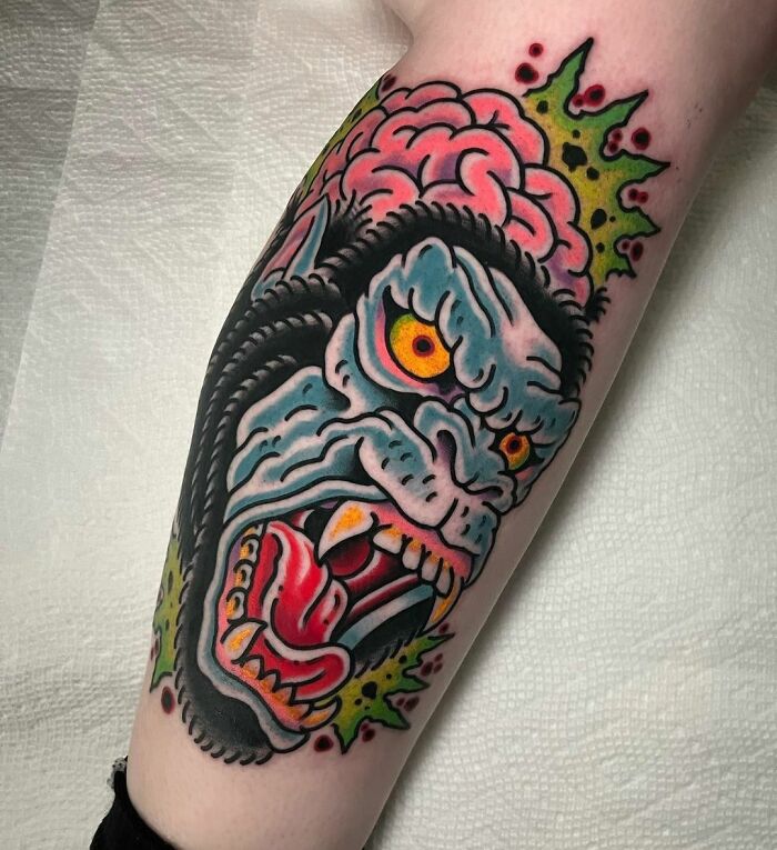 American traditional tattoo featuring a colorful, fierce monster design on forearm skin.