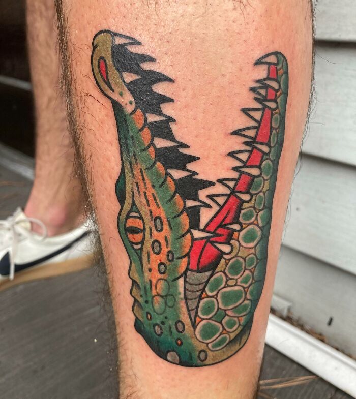 American traditional tattoo of a stylized alligator on a person's leg.
