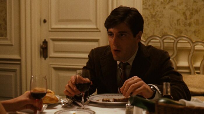 Michael Corleone drinking wine at the table 