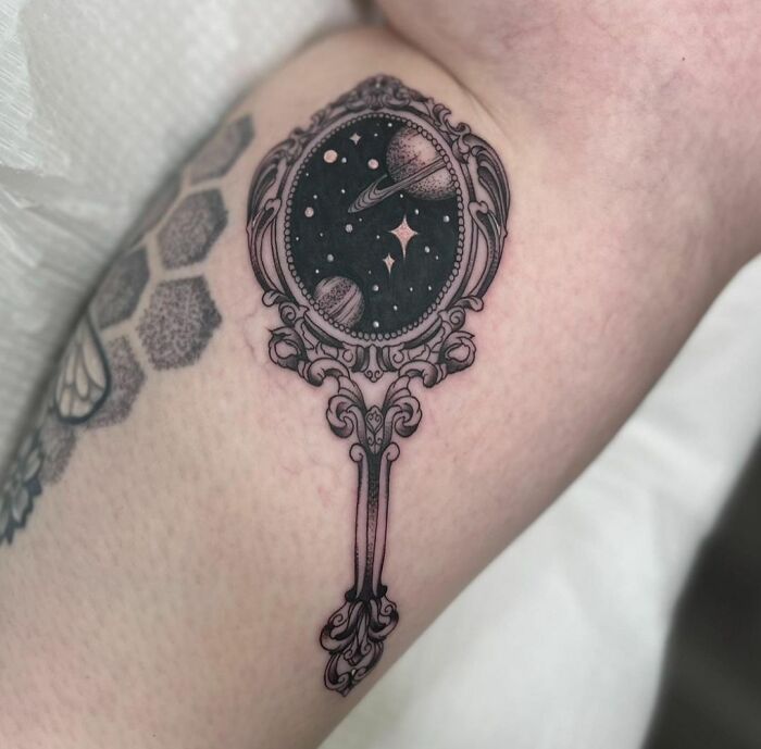 Vintage hand mirror with a space leg tattoo