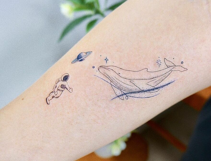 Space whale and astronaut arm tattoo