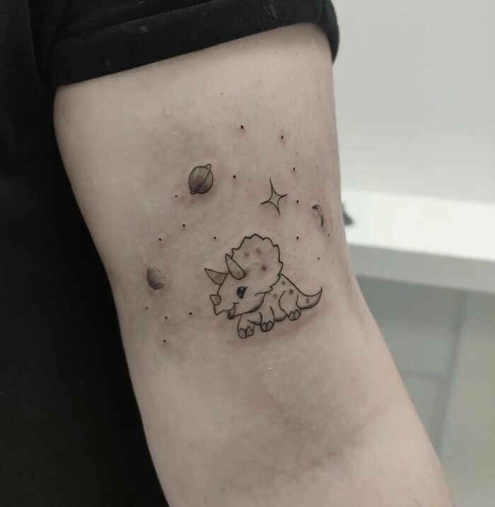 Space dinosaur arm tattoo