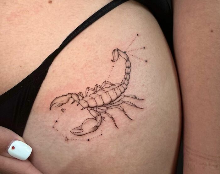 Scorpio zodiac tattoo design on person's upper arm, featuring constellation elements.