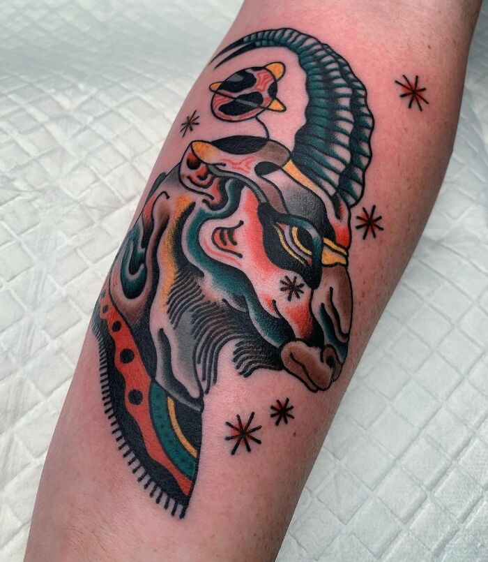 Colorful zodiac tattoo featuring an abstract Capricorn design on an arm.