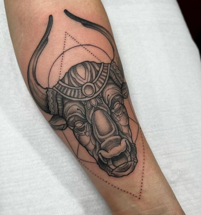 Bull zodiac tattoo with geometric patterns on forearm.