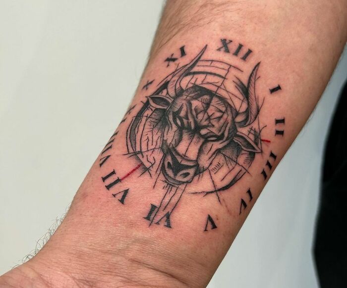 Zodiac tattoo of a geometric Taurus bull with Roman numerals on a forearm.