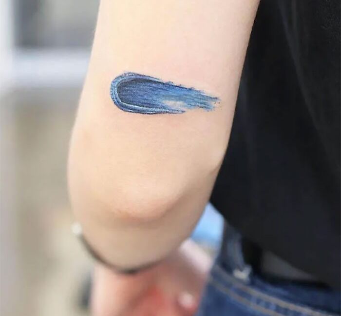 Blue brushstroke tattoo on the elbow