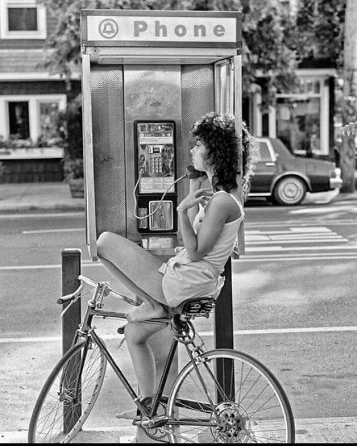 Mujer hablando en una cabina telefónica, años 80