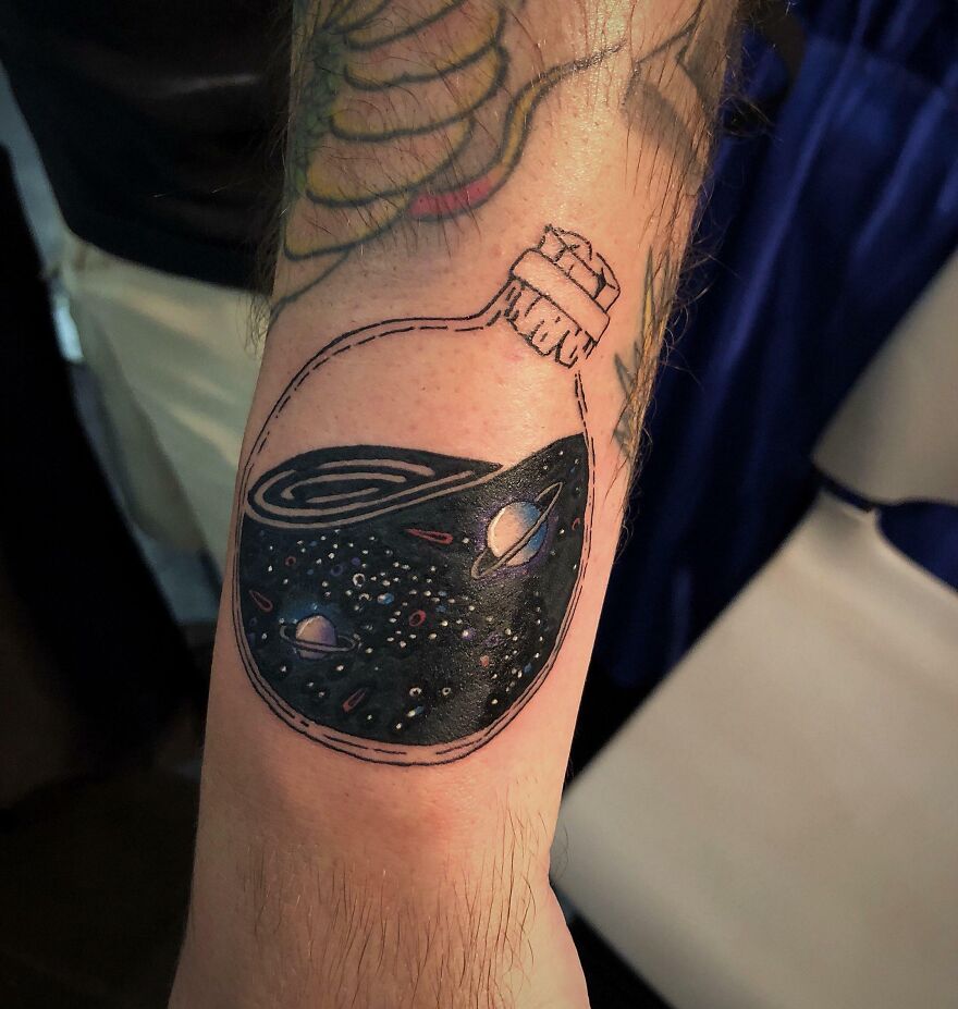 Space bottle tattoo on forearm
